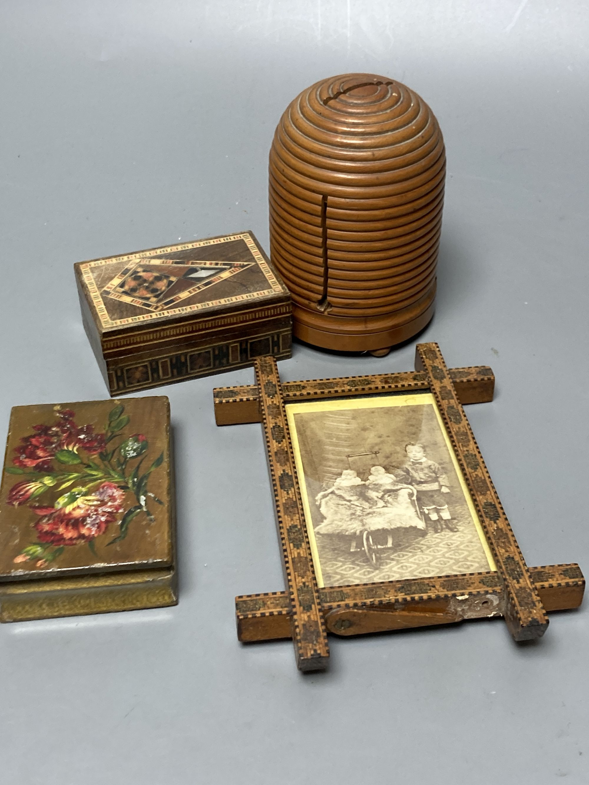 A Tunbridge ware tesserae mosaic photo frame, 15.3cm high, a Belgian Spa flower painted matchbox, a boxwood 'beehive' string box and a marquetry box